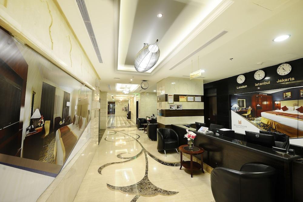Al Aqeeq Madinah Hotel Medina Exterior photo The photo shows the interior of a hotel lobby or reception area. It features a sleek, modern design with elegant marble flooring, decorative lighting fixtures on the ceiling, and a sophisticated color scheme. There are comfortable black seating areas