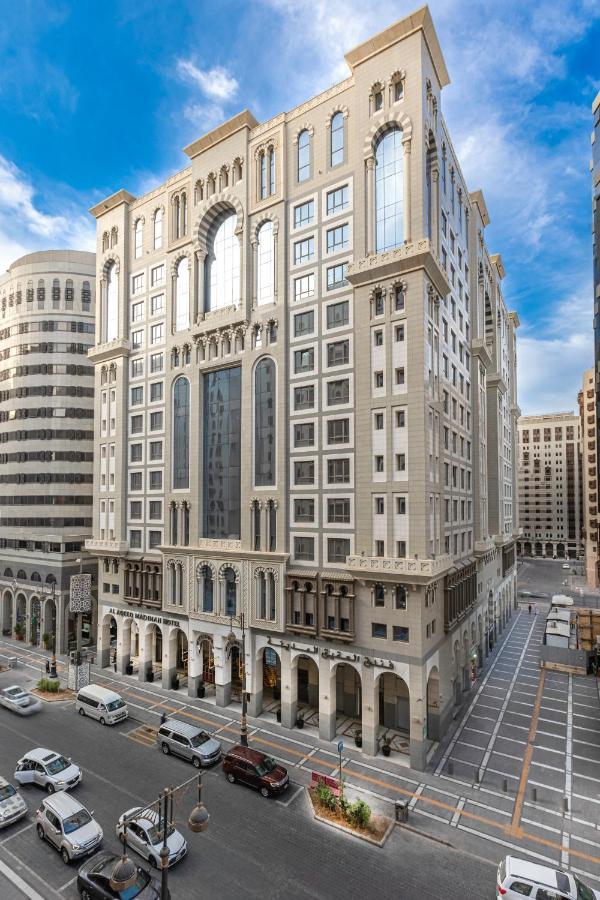 Al Aqeeq Madinah Hotel Medina Exterior photo The photo depicts a large, modern building with a distinctive architectural style. The structure shows a blend of classic and contemporary design elements, featuring ornate details, large glass windows, and a prominent central facade. Surrounding the
