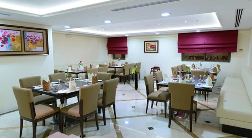 Al Aqeeq Madinah Hotel Medina Exterior photo The photo shows a well-decorated restaurant interior. It features several tables arranged neatly throughout the space, each set with chairs and tableware, including plates, glasses, and napkins. The flooring is a polished stone surface with a stylish