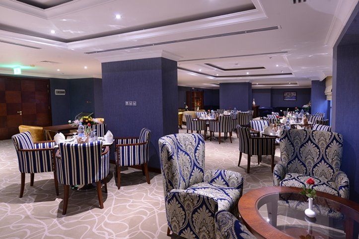 Al Aqeeq Madinah Hotel Medina Exterior photo The photo shows an elegant dining or lounge area. The space features plush seating with striped and patterned chairs, and tables set up for dining. The decor includes a rich color palette with blue walls and soft lighting creating a warm atmosphere. 